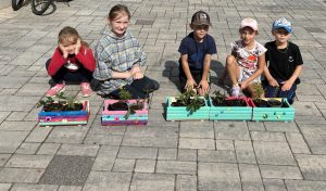 Kinder gestalten bunte Blumen- und Kräuterkästen
